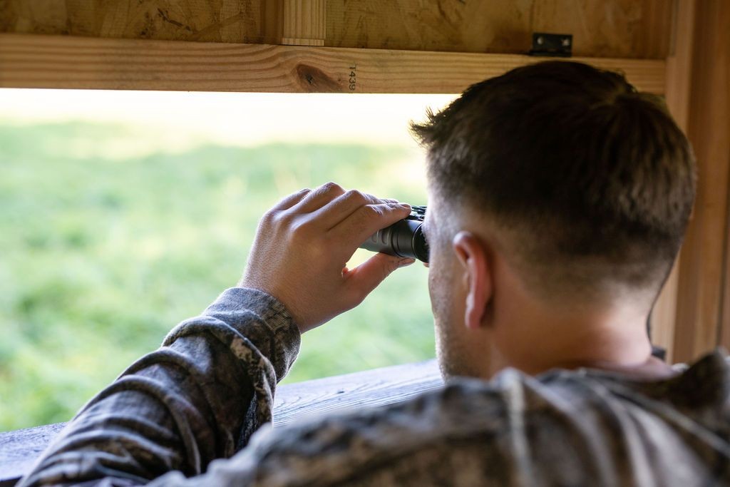 Hunter looking through binoculars in EZ Hunting Blind